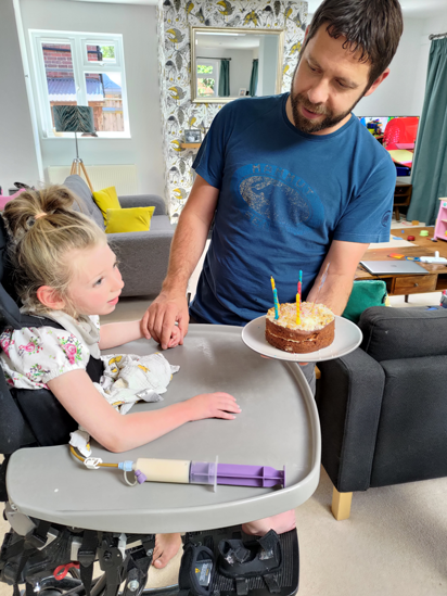 Photo of Sarah being presented with a birthday cake by her dad
