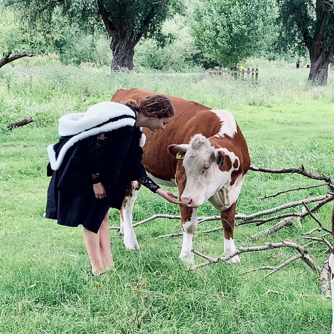 Photo of Sophie in a field petting a cow