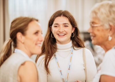 Photo of three women in conversation. They are all smiling and look happy.