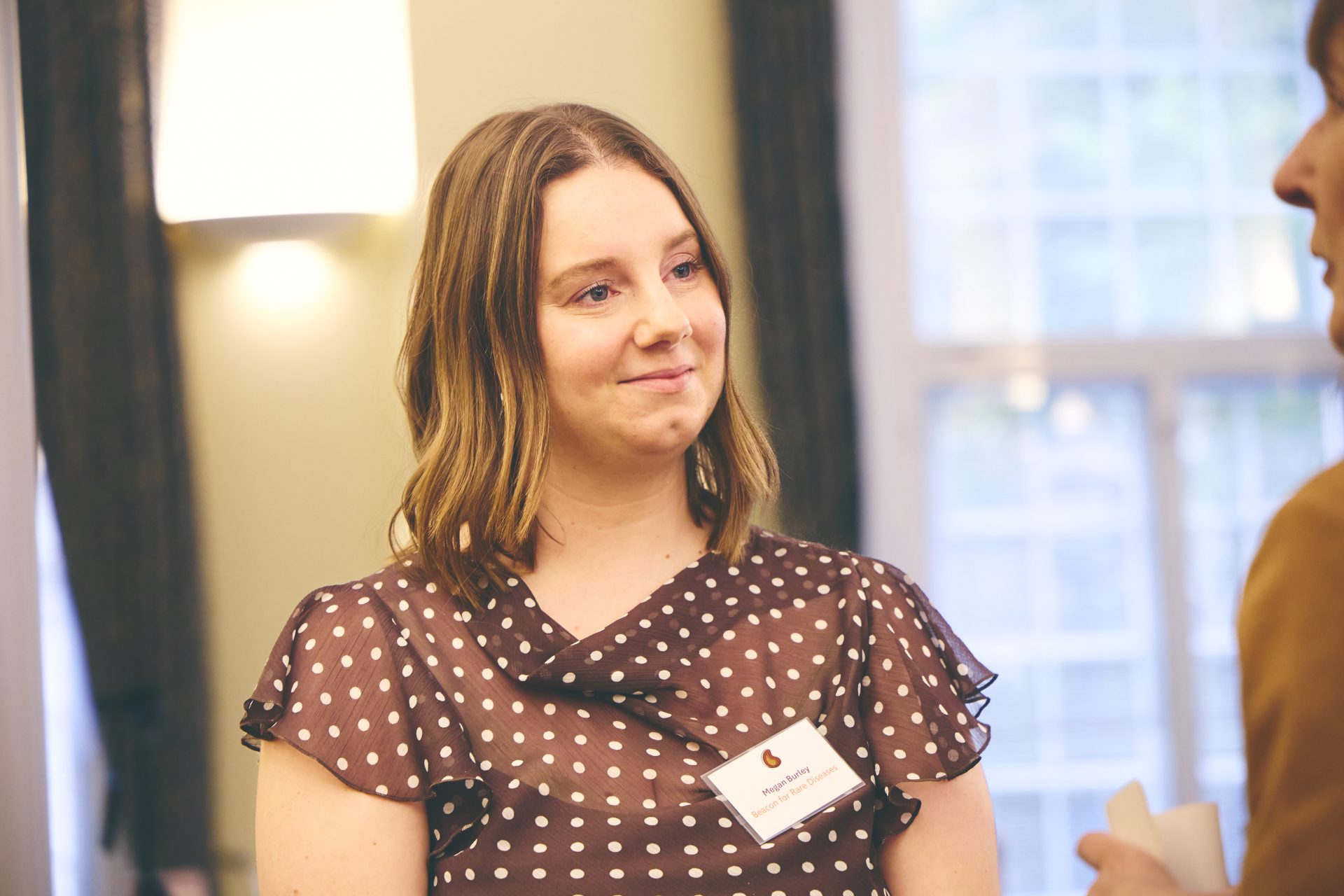 Photo of Megan holding up a sign that reads "I love Beacon because they have a tangible impact on patient groups and the rare disease community.