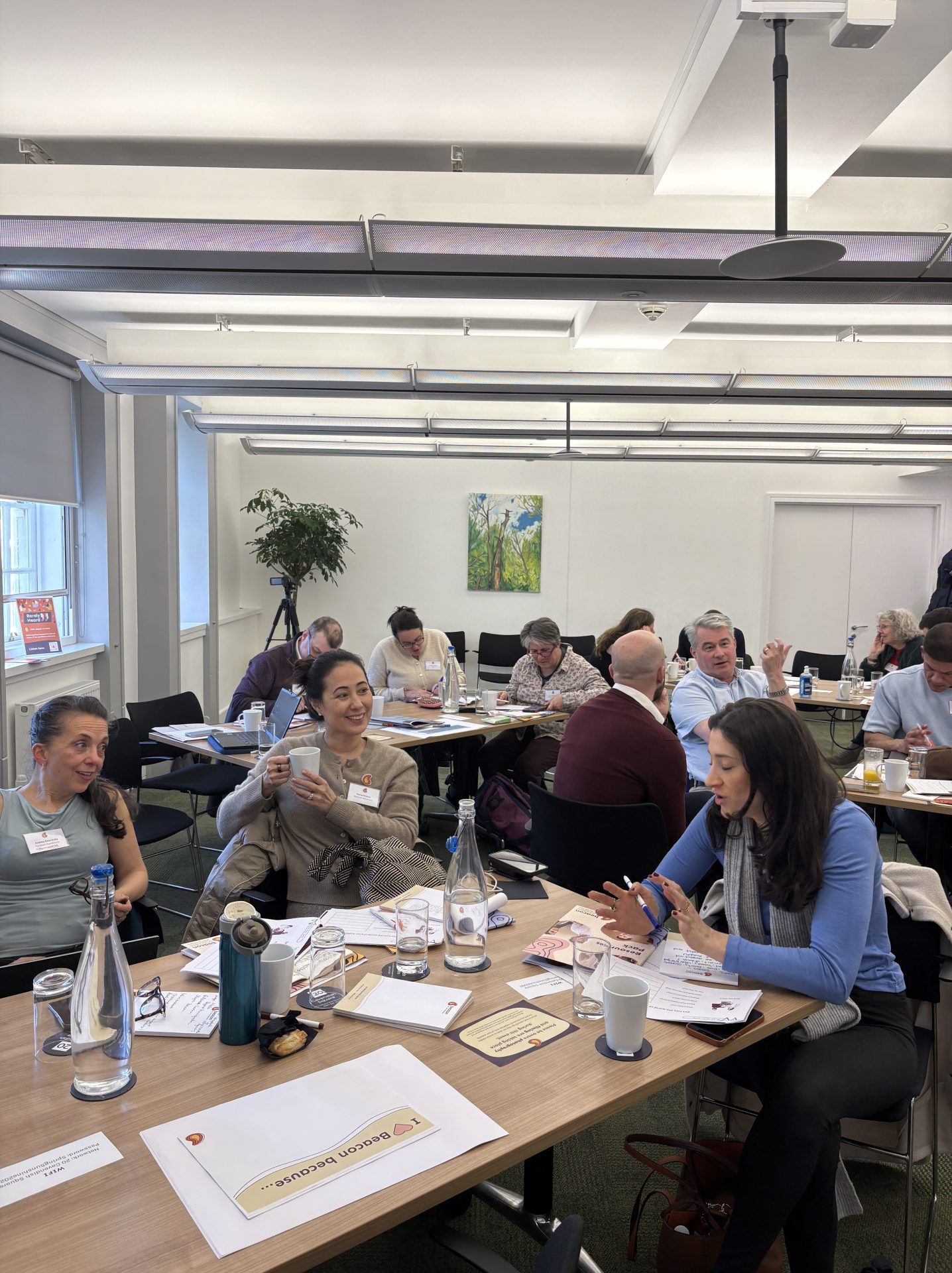 Room of masterclass attendees working together on tables in groups of around 4. 