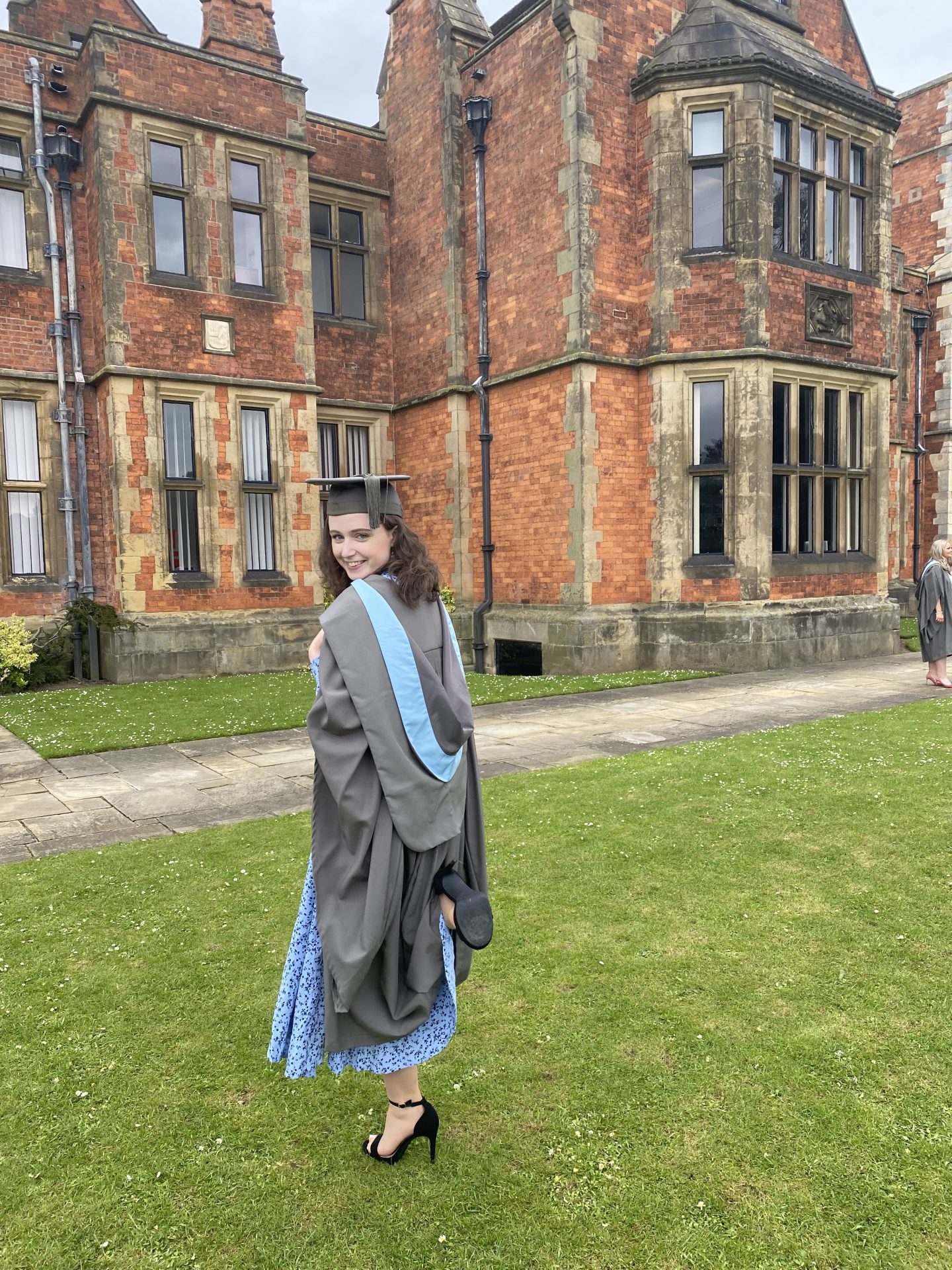 Maddy wearing graduation robes outside Heslington Hall at the University of York