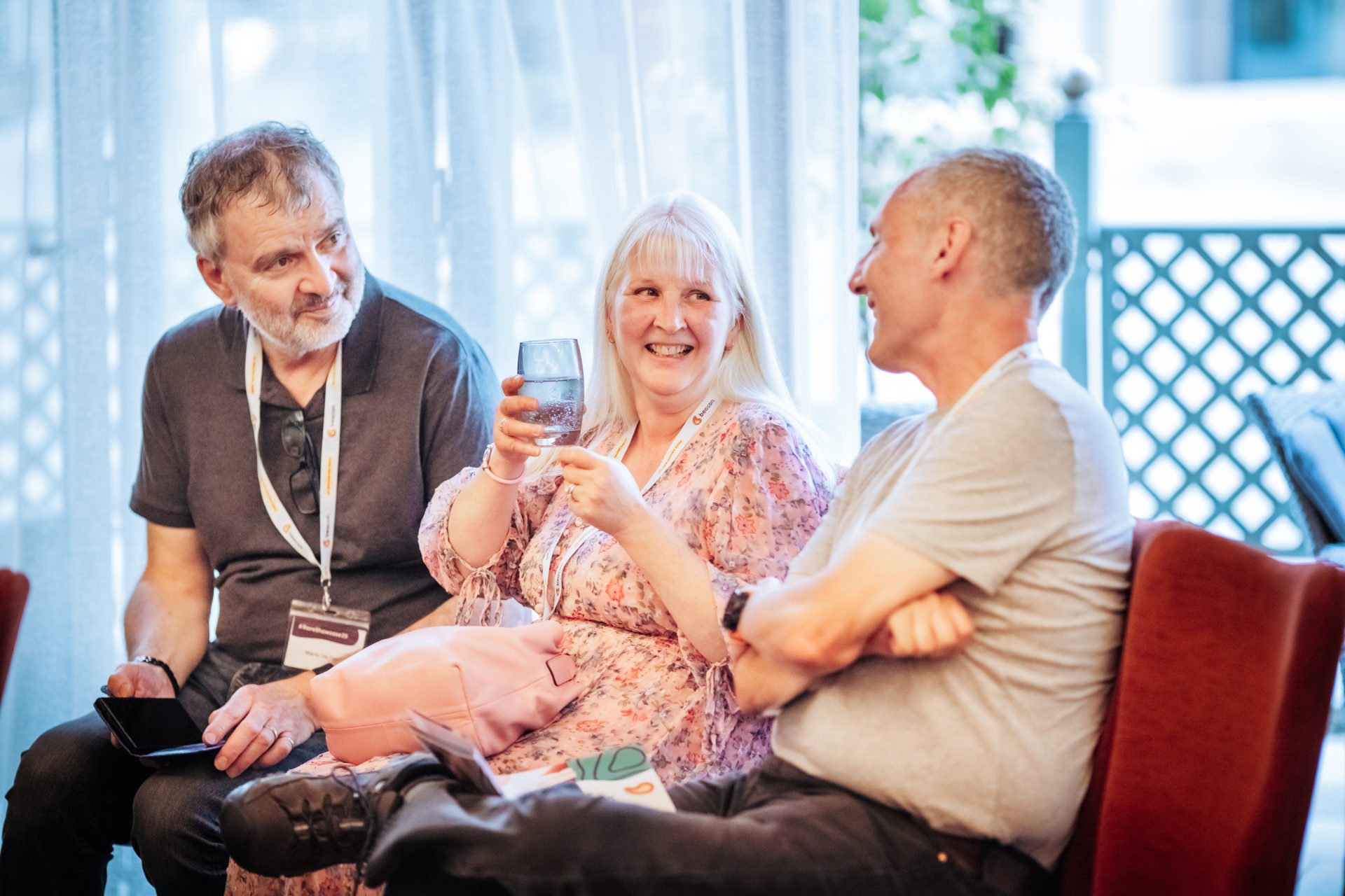 Photo of three women in conversation. They are all smiling and look happy. 